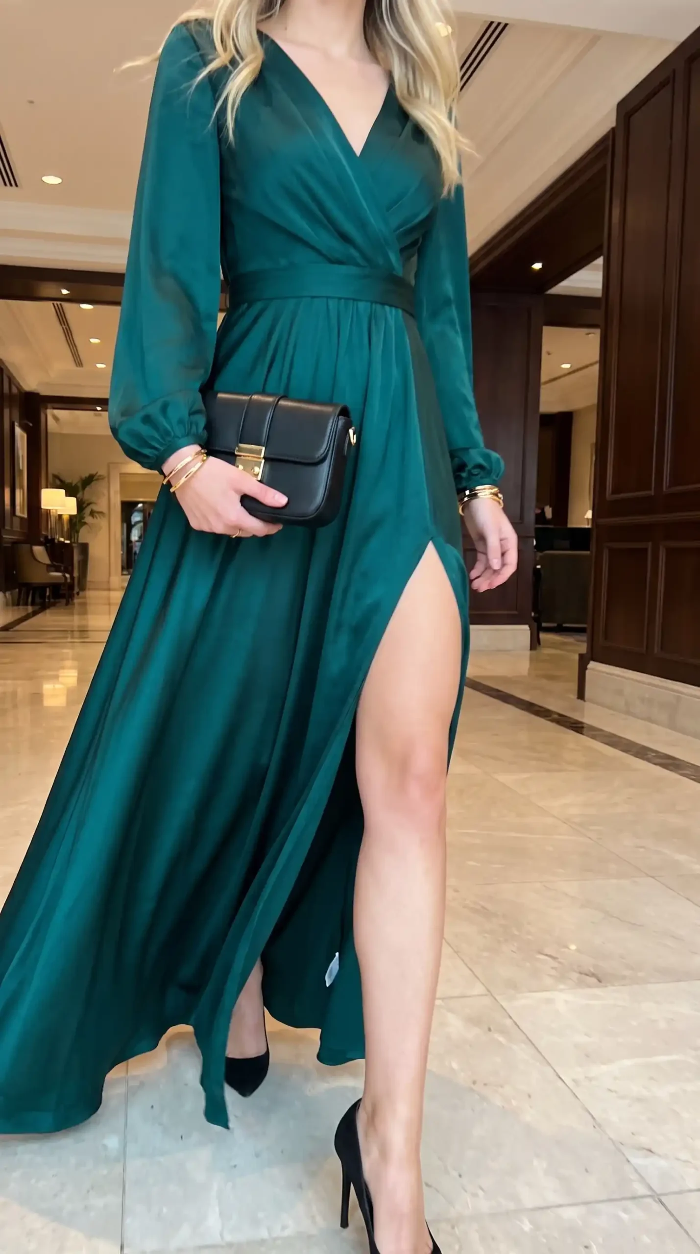 Woman wearing emerald green wrap v neck long sleeve thigh slit maxi dress with black bag