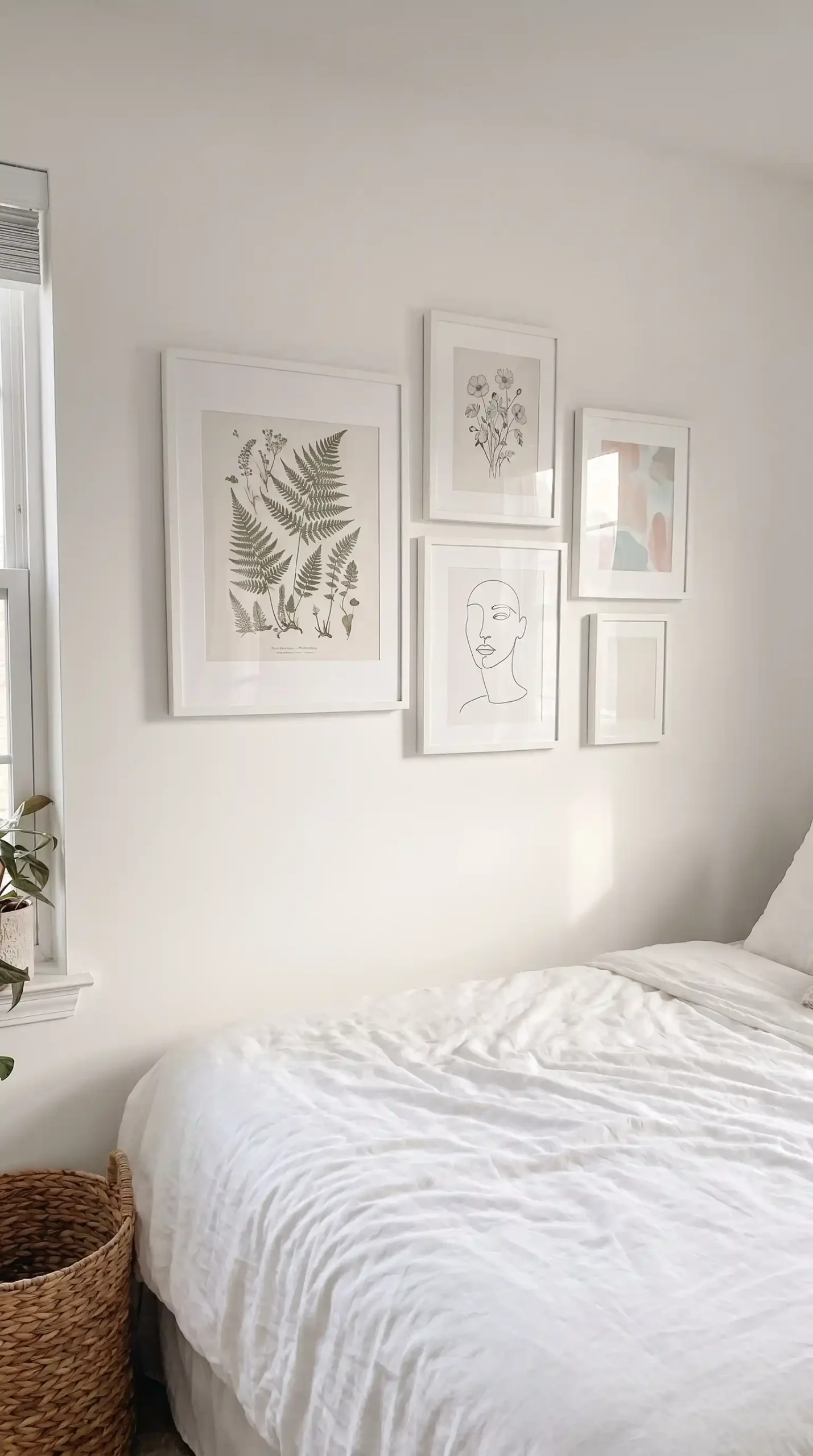 Feminine bedroom gallery wall with botanical prints line art and pastel abstract in white frames above bed