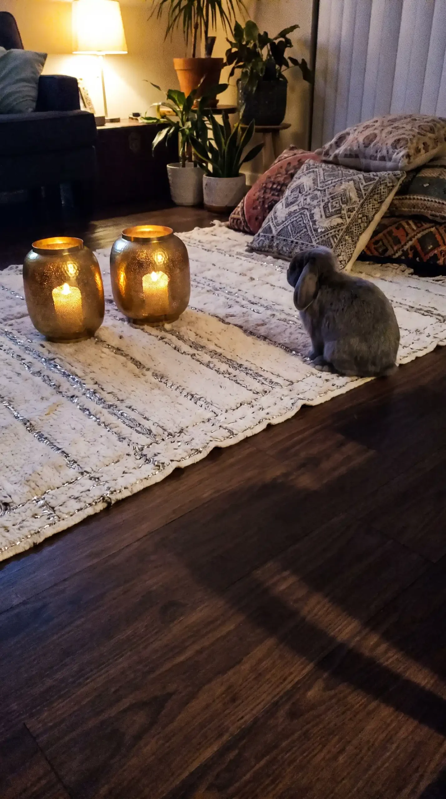 Vintage white and silver Moroccan wedding blanket used as floor rug with gold lanterns in warm boho living room