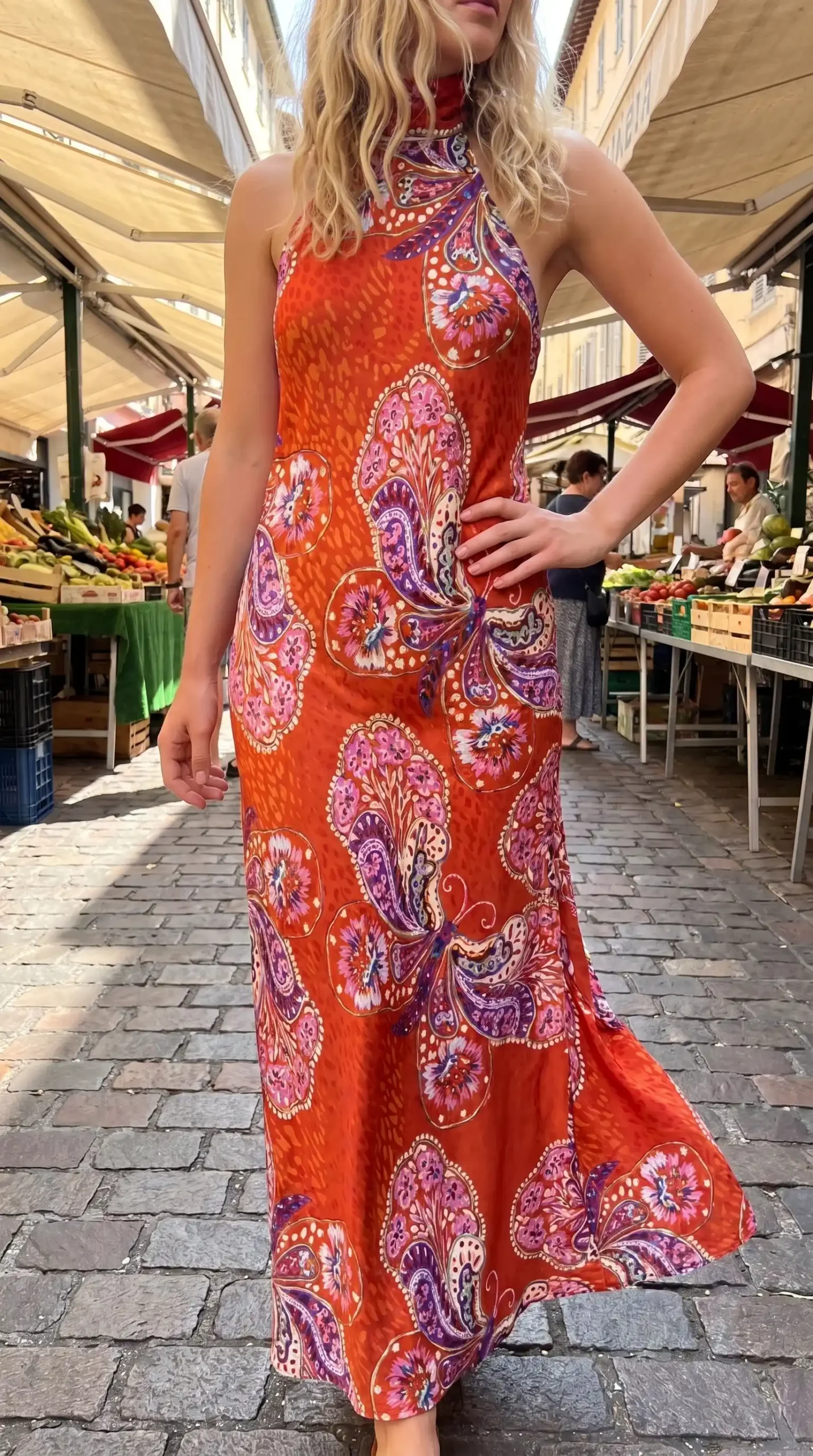 Woman wearing orange paisley print halter neck fitted maxi dress